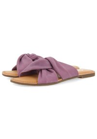 I sandali in tessuto viola presentano un design annodato con una suola piatta color beige. La texture è morbida, con una finitura liscia e uno stile minimalista.