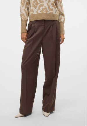 Pantalons plissés marron à coupe loose et jambes droites, fabriqués en tissu lisse. Associés à un pull beige à motifs et des escarpins.
