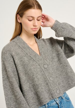 Grijze cropped cardigan van gestructureerd breimateriaal, met een V-hals, knoopsluiting en wijde mouwen. Gecombineerd met denim.