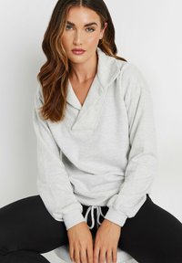 Pullover grigio chiaro con colletto drappeggiato, maniche lunghe e polsini elasticizzati. Coulisse all'orlo; tessuto morbido e texturizzato.