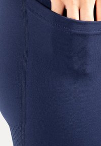 Marineblauwe sportleggings met een gestructureerd zijvak, gladde stof en flatlocknaden voor comfort en flexibiliteit.