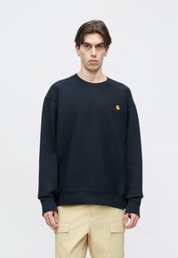 Μπλε ναυτικό φούτερ με στρογγυλή λαιμόκοψη, πέτα ώμοι, ριμπ μανσέτες και μικρό λογότυπο σε αντίθετα χρώματα στο στήθος. Μαλακή υφή.