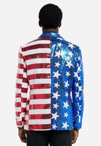 Paillettenblazer met een helft in rode en witte strepen, de andere helft in blauw met witte sterren. Geweven met glanzende pailletten, sluiting met één knoop.