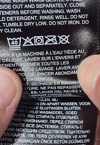 Vaskelapp med symboler: vask ved 40°C, ikke blek, tørk i tørketrommel ved lav varme, ikke stryk, ikke rense.