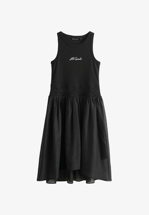 Črna obleka brez rokavov z nabranim pasom in večplastno krilom iz prosojnega materiala. Na sprednji strani je viden napis znamke.