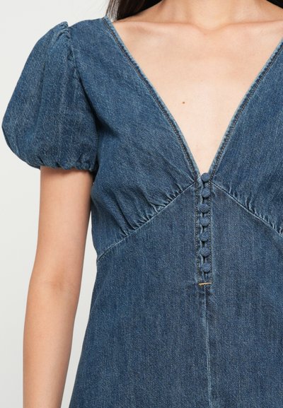 Denim kleita ar dziļu V veida kakla izgriezumu, pūkainām piedurknēm un dekoratīvām pogām centrā. Audums ir strukturēts ar zilu toni.