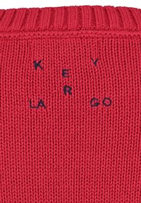 Tessuto a maglia rosso con lettere ricamate nere che formano la frase "KEV ER LA GO" disposte in modo sparso.