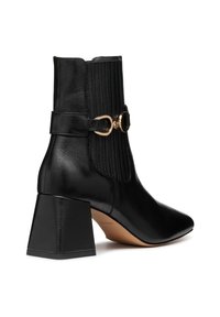 Stivaletto in pelle nera con punta affusolata, tacco a blocco piatto, dettagli a coste, accessorio in metallo dorato e una cintura laterale con fibbia.
