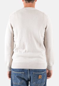 Maglione beige chiaro in maglia con colletto e polsini a coste, caratterizzato da un motivo testurizzato. Indossato al contrario, abbinato a jeans di denim.