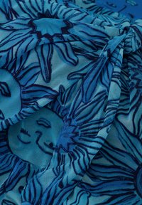 Blauwe stof met zon- en gezichtspatronen, met een gladde textuur. Het ontwerp bevat donkere lijnen en speelse motieven op een lichtblauwe achtergrond.