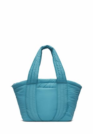 Svetlomodrá prešívaná taška na rameno so širokými polstrovanými rukoväťami a predným otvoreným vreckom, zobrazená na bielom pozadí.