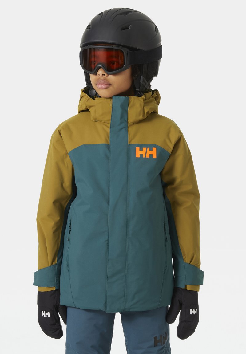 Skijacke in Grün und Senfgelb, mit hohem Kragen, Logo auf der Brust und Reißverschlusstaschen. Mattes Finish, kombiniert mit schwarzen Handschuhen.