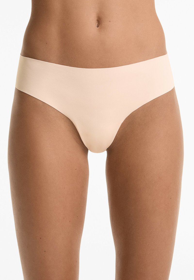 Beige naadloze bikini slips met een low-rise taille en zachte, gladde stof, bieden een minimalistisch ontwerp zonder zichtbare lijnen.