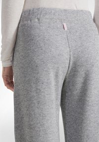 Pantaloni de jogging gri, confecționați dintr-un material moale, cu un aspect texturat. Dispune de un talie elastică și un mic eticheta roz în spate.