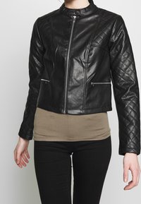 Giubbotto in pelle nera con spalle trapuntate, design aderente, chiusura con zip sul davanti e tasche laterali. La finitura testurizzata aggiunge dettagli e stile.