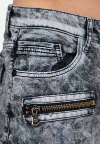 Jeans in denim con una finitura grigia sbiadita, dotati di una tasca frontale e una tasca con zip in metallo dorato. Tessuto tessuto con cuciture visibili.