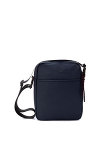 Bolso bandolera de color azul marino hecho de nailon texturizado con forma rectangular, correa ajustable, bolsillo frontal y detalles en cremallera de color rojo contrastante.