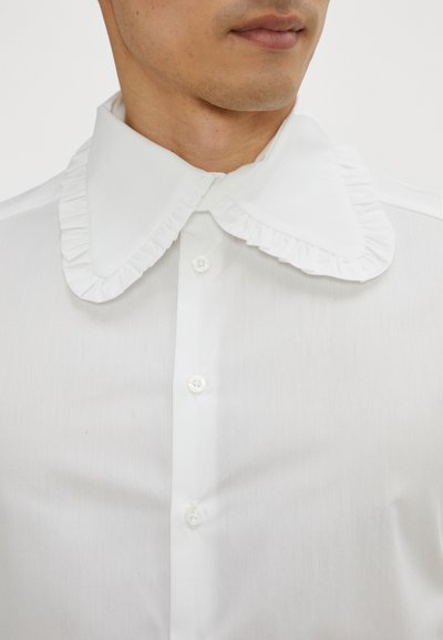 White button-up shirt with a ruffled collar and plain texture, featuring clear buttons along the front and a tailored fit.