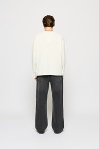Lys beige oversized sweatshirt med lange ærmer, parret med løse mørke grå jeans med to baglommer og lige snit.