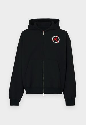 Black zip-up hoodie made of soft fabric. Features a front kangaroo pocket and a round logo with a red silhouette on the left chest.