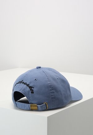 Jasnoniebieska czapka z daszkiem z regulowanym paskiem i mosiężną klamrą, wyszyty czarny tekst na tylnej stronie, umieszczona na białej powierzchni.