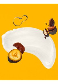 Mancha de crema blanca con fruta salak en rodajas y vainas de cacao agrietadas sobre fondo amarillo brillante.