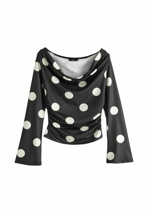 Zwarte top met lange mouwen, grote witte polka dots, gedrapeerde halslijn en gerimpelde zijkanten, die een strakke silhouet bieden.