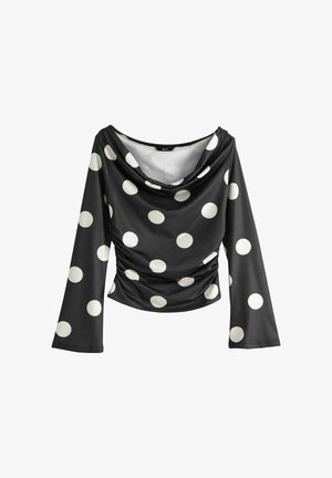 Must pikkade varrukatega topp suurte valgete täppidega, drapeeritud kaelusega ja külgedel kortsudega, mis annavad figuurile keha järgiva silueti.