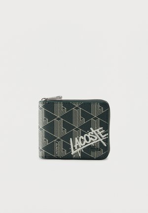 Μαύρο πορτοφόλι με φερμουάρ και γεωμετρικό λευκό μοτίβο "L" και μεγάλο λευκό λογότυπο Lacoste σε στυλ γκράφιτι μπροστά.