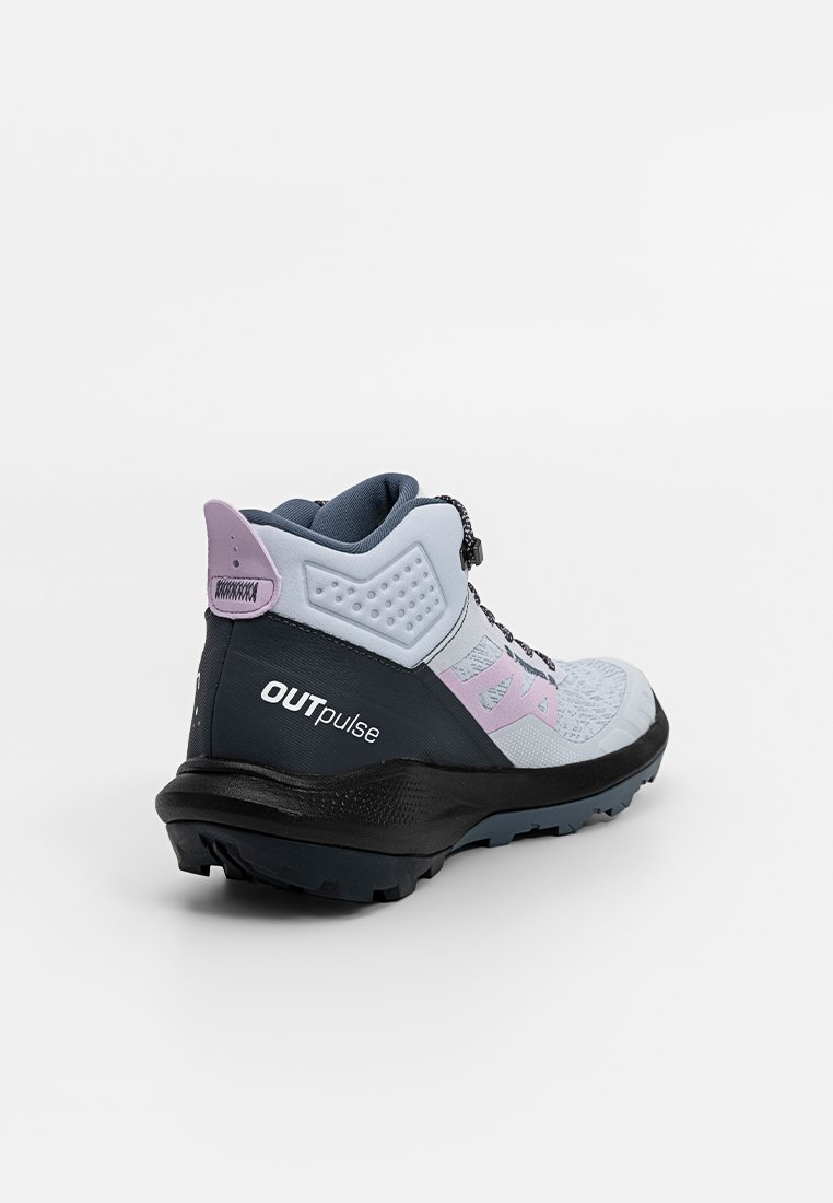 Zapatilla de senderismo de corte medio en azul claro y gris oscuro. Cuenta con un upper texturizado, acentos en rosa y una suela de goma negra con banda de rodadura acanalada.