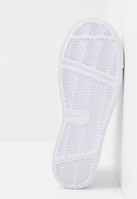 Vit sneakersula med fiskbensmönster, texturerad för grepp. Tillverkad av gummi, med förstärkt tå och släta kanter.