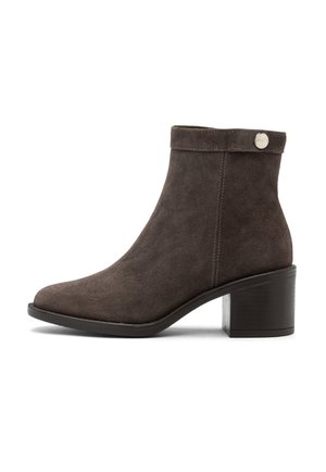 Brown suede ankle boot with a rounded toe, short shaft, and a block heel. Features a stitched design and a small metallic logo accent.