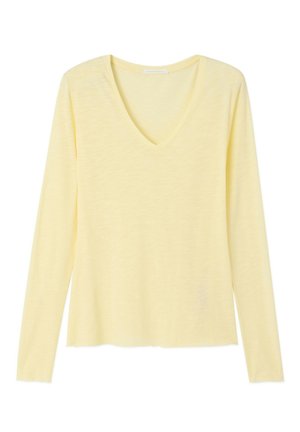 Camiseta de manga larga de color amarillo pálido con cuello en V, tejido ligero ligeramente texturizado y ajuste holgado.