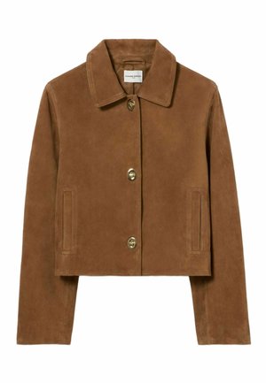 Jeune femme portant une veste marron boutonnée, un chemisier rayé bleu avec un nœud, une jupe en cuir noire, des chaussettes bleu marine et des chaussures marron sur fond blanc.