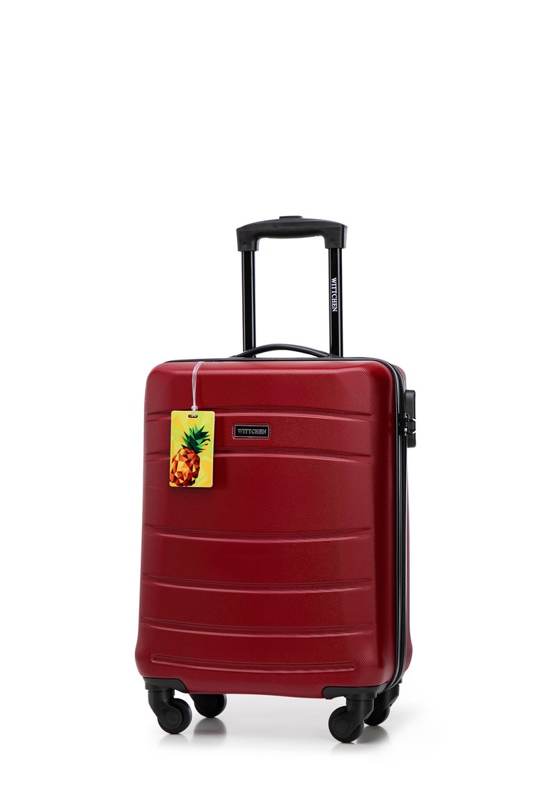 Red hardshell suitcase with horizontal ridges, black telescopic handle, and four spinner wheels. Features a pineapple tag.