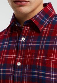 Camicia di flanella a quadri rossi e blu con colletto button-down, caratterizzata da bottoni bianchi, una texture sottile e un dettaglio con taschino anteriore.