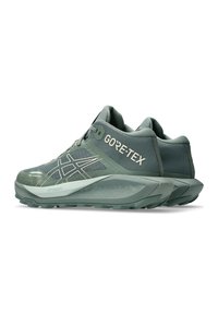 Green GORE-TEX trail running shoes with textured surface, reflective accents, cushioned sole, and rugged outsole for traction.