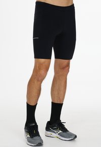 Svarta idrottsshorts med en tät passform, tillverkade av stretchigt tyg, med sidofickor och reflexdetaljer.