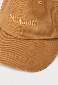 Svijetlosmeđi kroko šešir s zakrivljenim rubom i "PALLADIUM" izvezenim u odgovarajućoj niti na prednjem panelu.