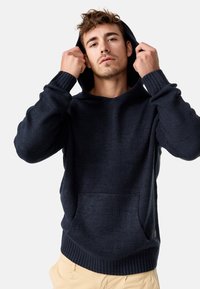 Hoodie bleu marine foncé en tissu tricoté texturé, avec une grande poche avant, des poignets côtelés et une capuche avec cordon de serrage.