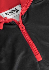 Sort zip-opp tøj med en fremtrædende rød lynlås og krave. Lynlåsen har en stjernesformet trækknap. Mærket læser "WeeDO funwear."