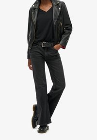 Black leather biker jacket, deep V-neck black shirt, tapered black jeans, and black lace-up boots with a chunky rubber sole.