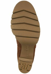 Zapato de ante marrón con suela de goma marrón claro que presenta profundos surcos para tracción. Punta redondeada y textura suave en la parte superior.