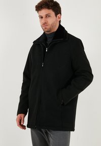Giacca nera con zip e collo alto. Realizzata in materiale morbido, presenta una chiusura con zip e tasche laterali. Texture liscia senza motivi.