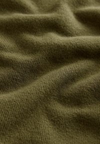 Olijfgroen textiel met een ribbelpatroon, voorzien van zachte vezels en zachte golven, wat diepte en dimensie aan het materiaal geeft.
