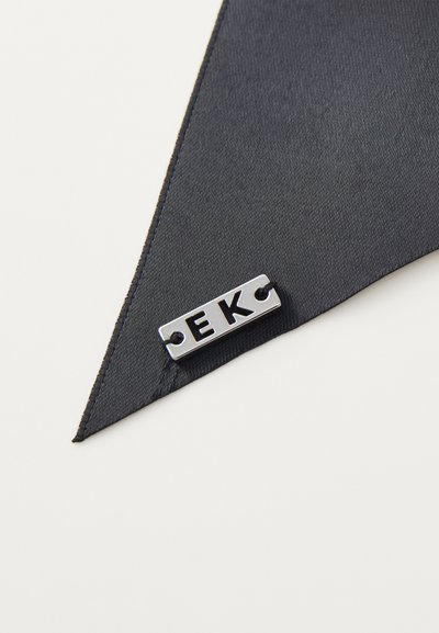 Čierny saténový materiál s špicatým okrajom má kovovú značku s vygravírovaným nápisom "EK". Hladká textura, minimalistický dizajn a jemný lesk.