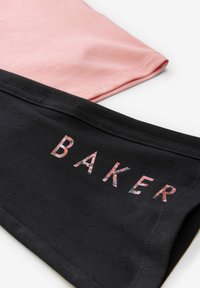 Dve tričká: jedno ružové a jedno čierne. Čierne tričko obsahuje nápis "BAKER" v kvetinovom vzore. Jemná bavlnená textúra.