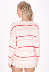 Maglione lavorato a maglia bianco con strisce rosa e rosse, caratterizzato da una vestibilità ampia, fessure laterali e dettagli texture a macchie in tutto il capo.
