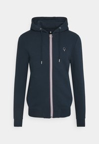 Sudadera con cremallera en color marino, con un bolsillo frontal, capucha ajustable con cordón y rayas en blanco, rojo y azul a lo largo de la cremallera. Presenta un pequeño logo en el pecho.