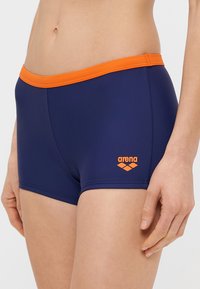 Μπλε σκούρο σορτς κολύμβησης με πορτοκαλί ελαστική μέση, με μικρό πορτοκαλί λογότυπο Arena στο πλάι, κατασκευασμένο από λείο, ελαστικό υλικό.